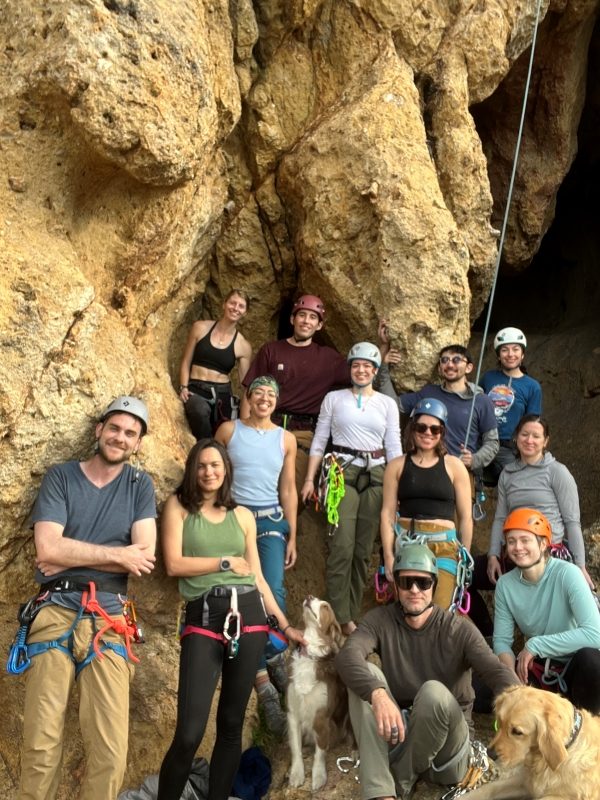 Group portrait of rock climbers and 2 dogs at the crag.