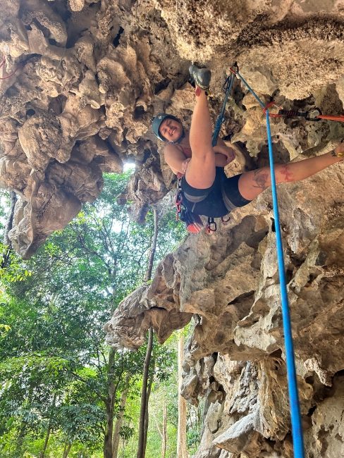 Woman rock climber hanging for photo during a climb outside.