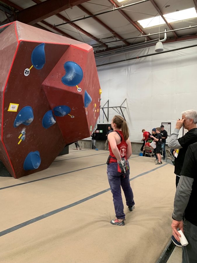 Woman rock climber reviewing climb at climbing competition.