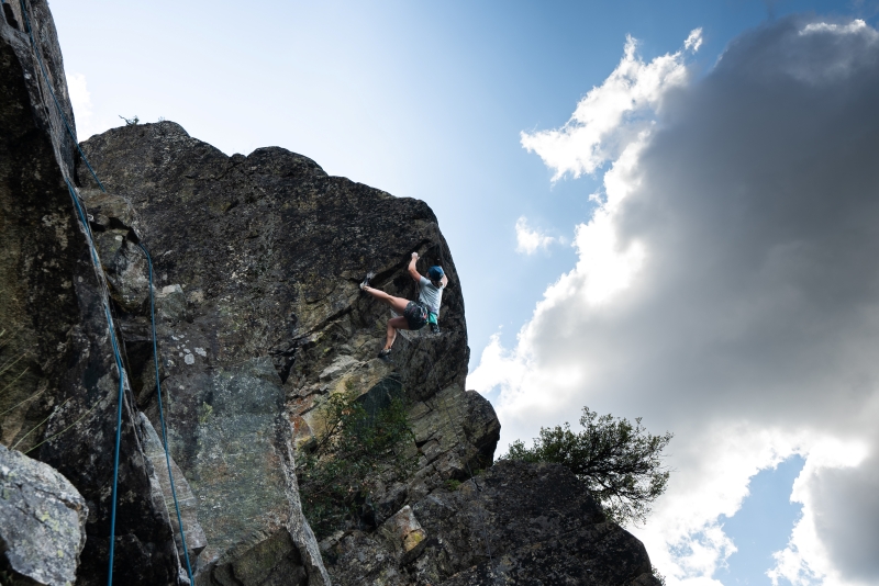 Rock climber completing a hard move on outdoor rock climb.