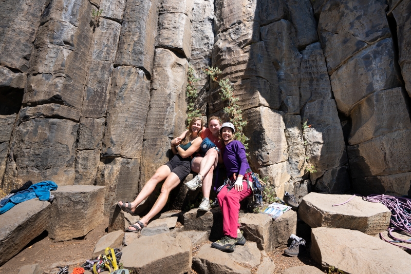 Group of 3 climbing friends posed for a portrait at outdoor crag.