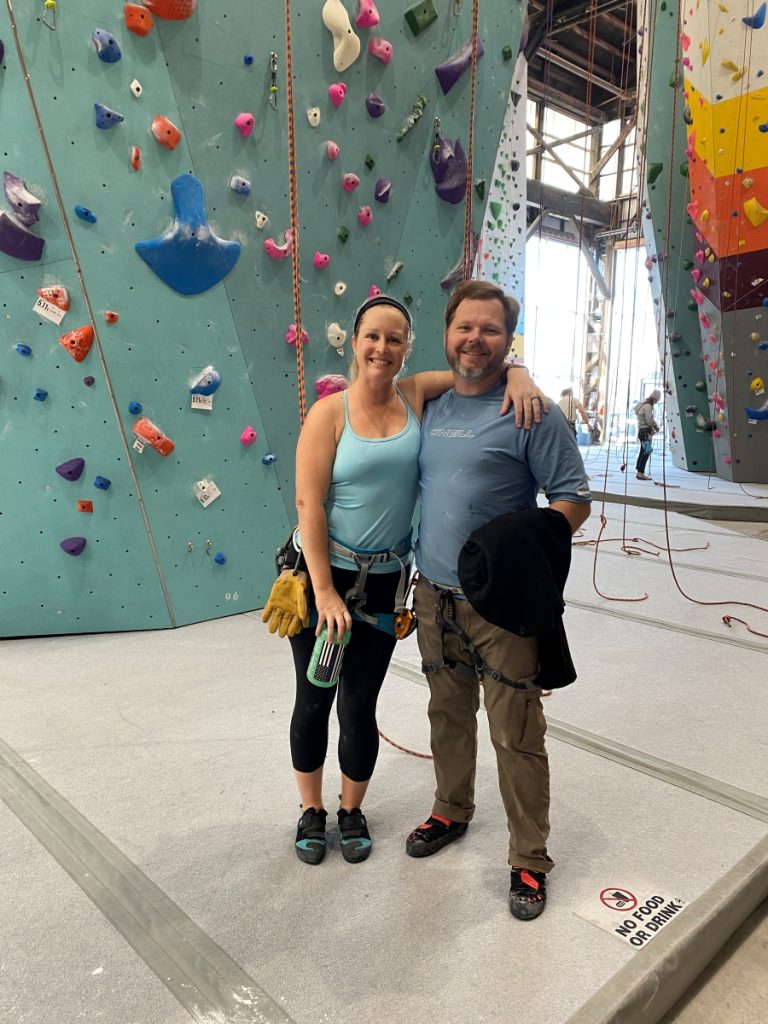 Woman and man posed for portrait at a rock climbing gym.