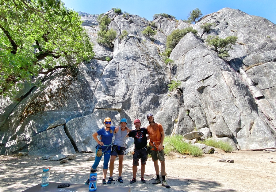 Group portrait of four rock climbers in front of granite rock wall in Yosemite.