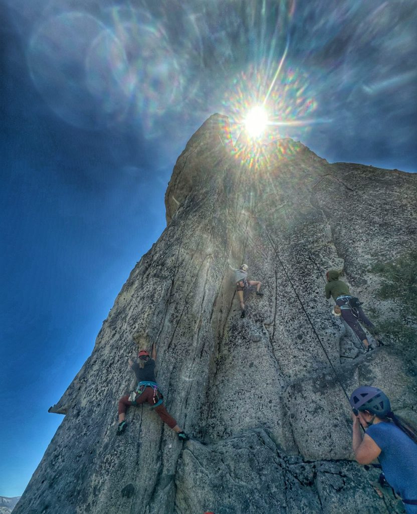 Two women rock climbing while two women belay from below at Phantom Spires rock climbing area in Tahoe, CA.