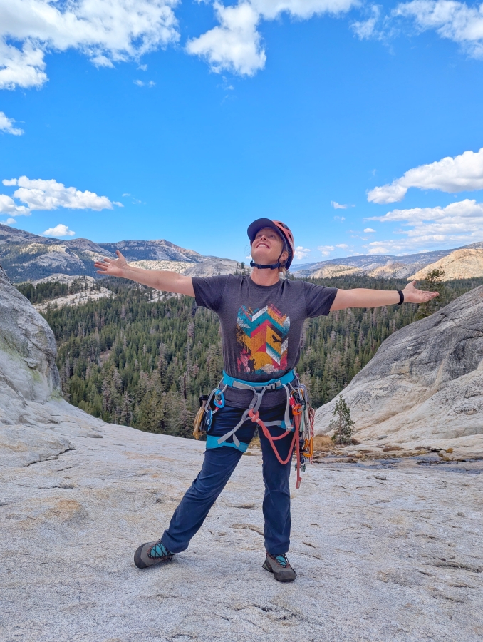 Woman rock climber smiling while enjoying the view at Tuolumne Meadows, Yosemite.