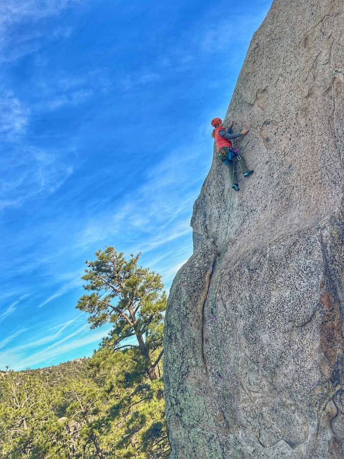 Woman rock climber leading sport climbing route outside in Big Bear, CA.