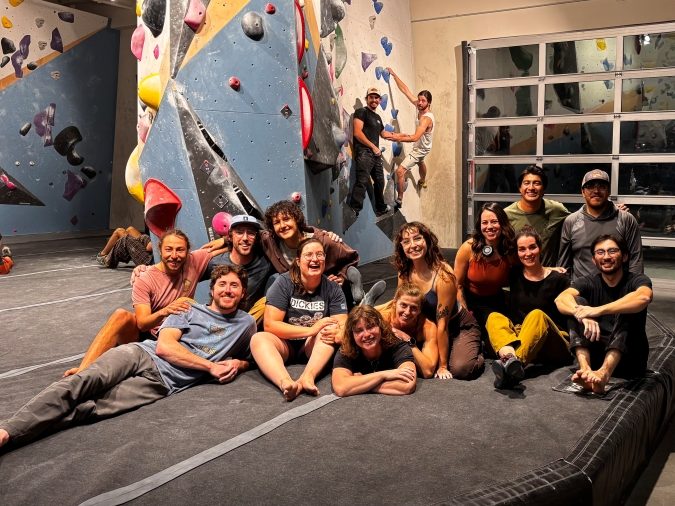 Group portrait of climbers in front of bouldering wall at Session climbing gym.