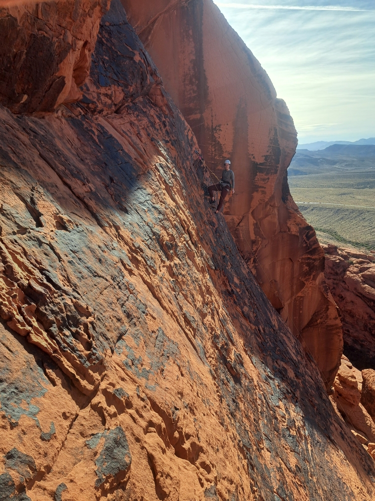 Woman rock climber posing for portrait mid-climb at Red Rocks.