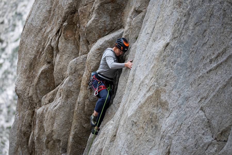 Woman rock climbing on granite rock wall at Pine Creek Canyon.