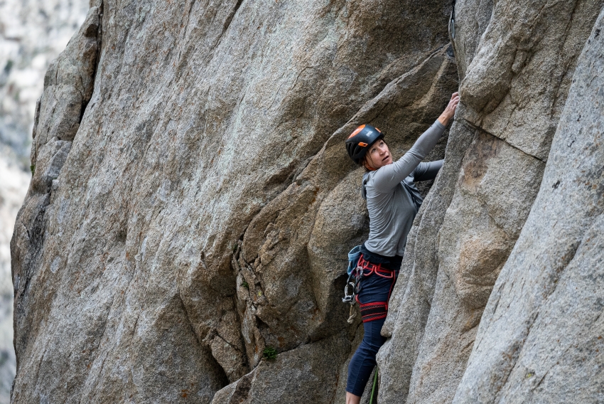 Woman rock climbing on granite rock wall at Pine Creek Canyon.