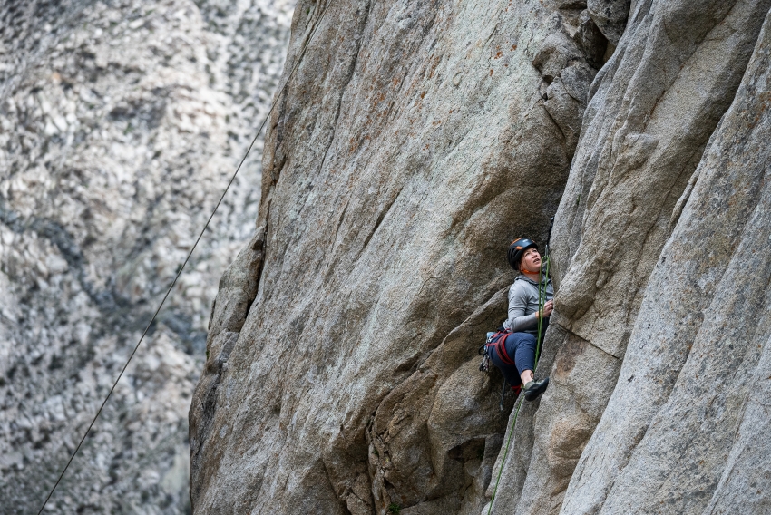 Woman rock climbing on granite rock wall at Pine Creek Canyon.